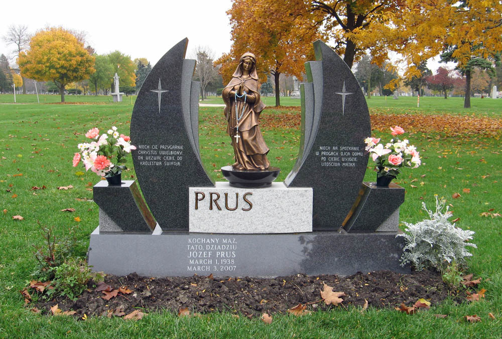 Family monument in dark gray granite with statue of Mary